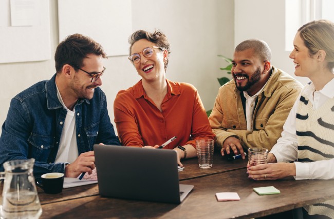Employees sitting at a table discussing 2024 wellbeing trends